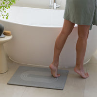 Original Current bath stone in Ash next to free-standing tub in minimal bathroom. 