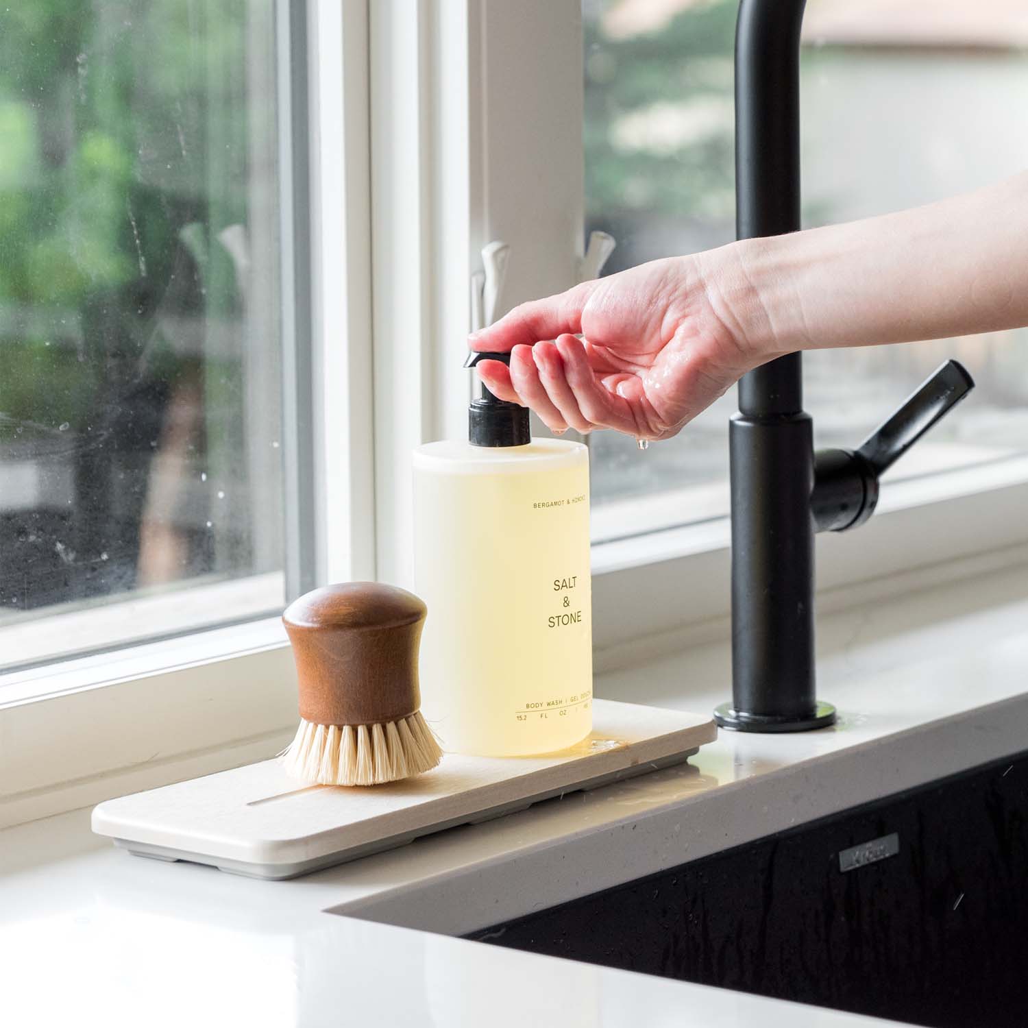soap dispenser on top of stone sink organizer on kitchen counter