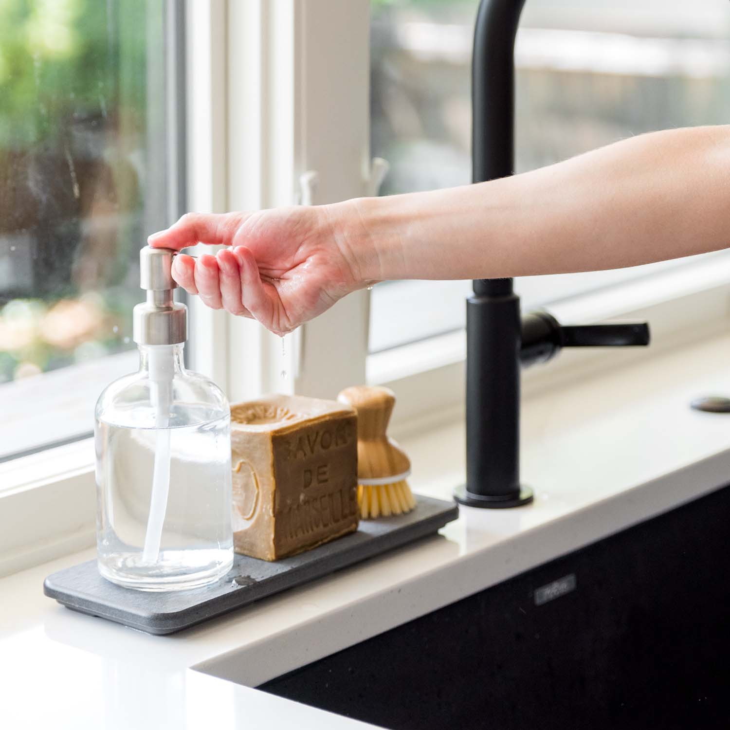 woman getting soap from bottle on stone sink caddy in slate color