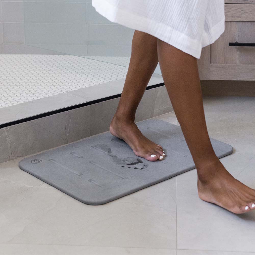 person stepping out of shower onto bath stone