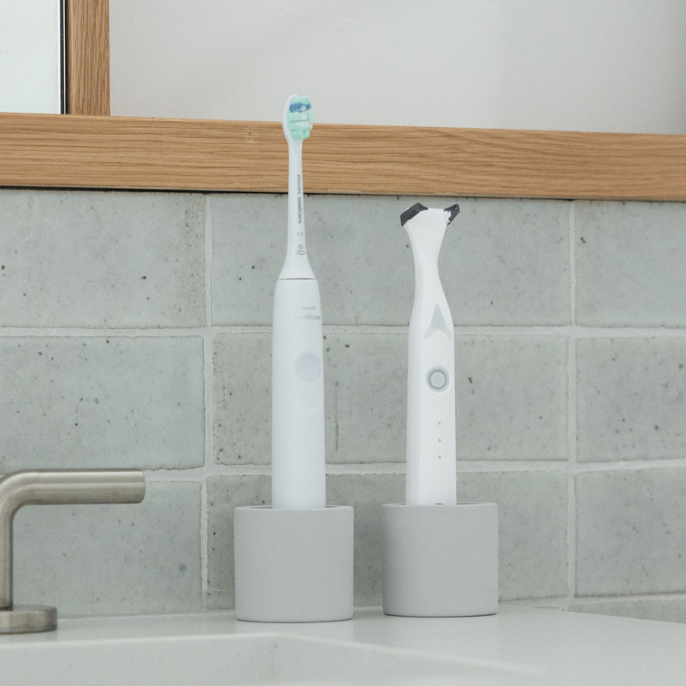 Two stone toothbrush holders, one holding an electric toothbrush and one holding an electric flosser, on a bathroom counter