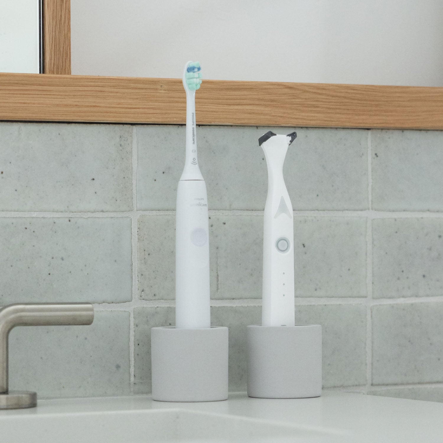 Two stone toothbrush holders, one holding an electric toothbrush and one holding an electric flosser, on a bathroom counter
