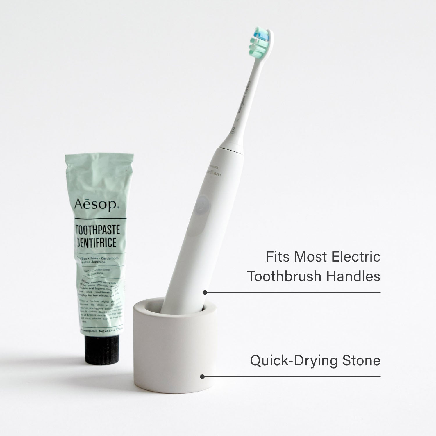 Stone toothbrush holder with an electric toothbrush next to toothpaste with product feature text overlaid