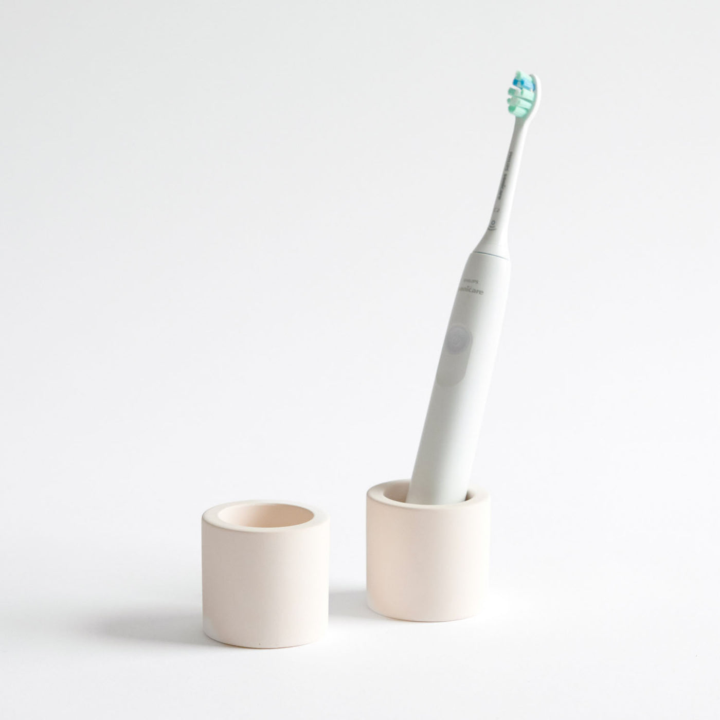 Two stone toothbrush holders, one with an electric toothbrush inside on a white background