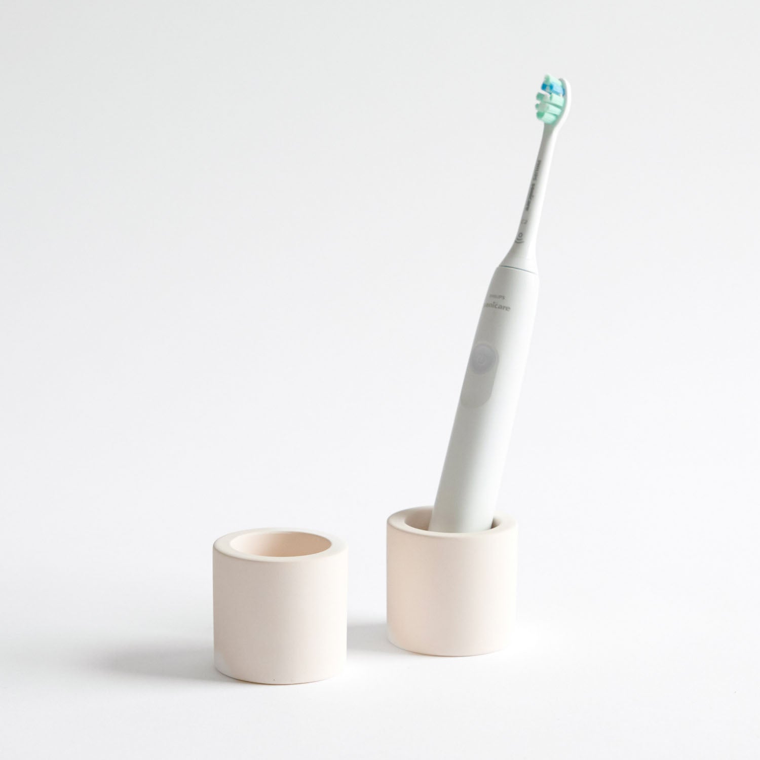 Two stone toothbrush holders, one with an electric toothbrush inside on a white background