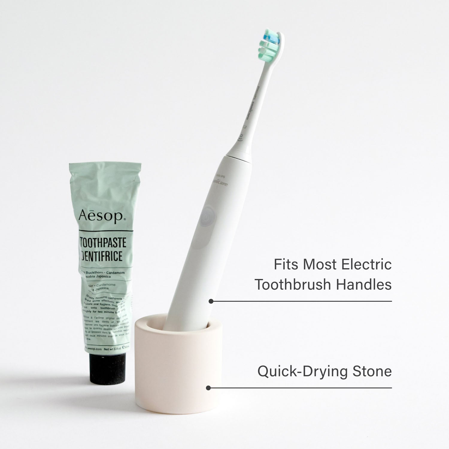 Stone toothbrush holder with an electric toothbrush next to toothpaste with product feature text overlaid