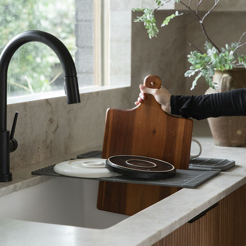 cutting board being inserted into over the sink dish drying pad